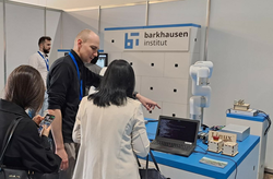 An employee of the Barkhausen Institut points to the laptop screen and explains to an interested person.